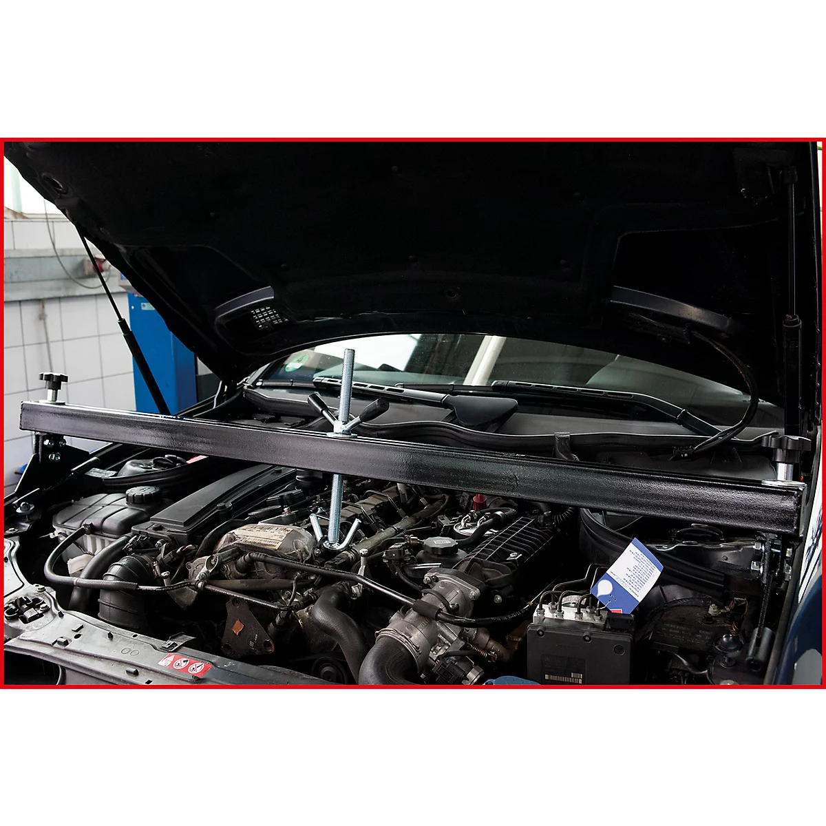 Motorraum eines Autos mit Werkzeug. Ein schwarzer Balken ist über dem Motor befestigt.